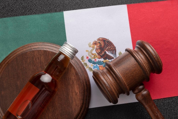 Alcoholfles en houten hamer op de vlagachtergrond van Mexico Concept alcohol en conflicten met de wet in Mexico