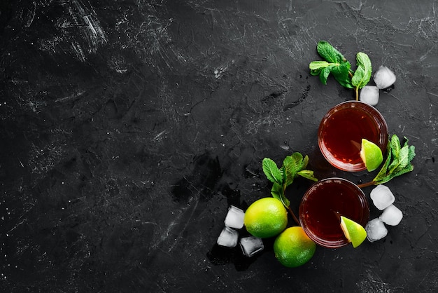 Alcoholic Beverage Rum lime and mint on a black stone background Top view Free space for your text