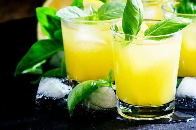 Cocktail alcolico smash di basilico con basilico verde gin sciroppo di zucchero succo di limone e ghiaccio su sfondo nero fuoco selettivo