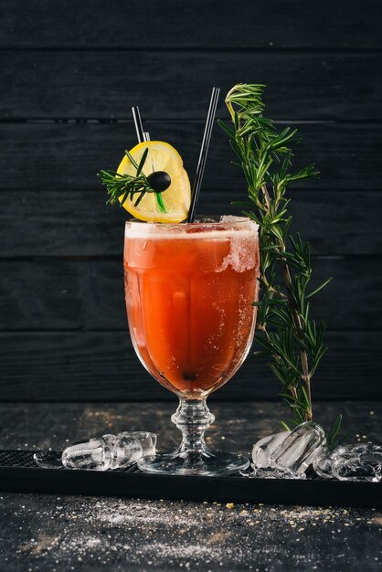 Alcoholic Cocktail Bloody Mary Tomato juice and rosemary On a black wooden background