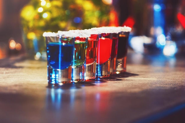 Alcoholic cocktail row on bar counter, colorful shooters cocktails drinks