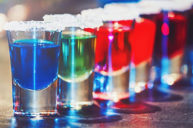 Alcoholic cocktail row on bar counter, colorful shooters cocktails drinks