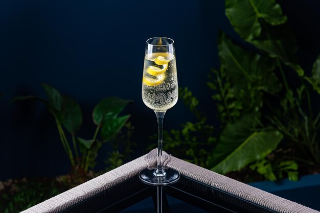 Alcoholic cocktail on a transparent table against a blue background and plants