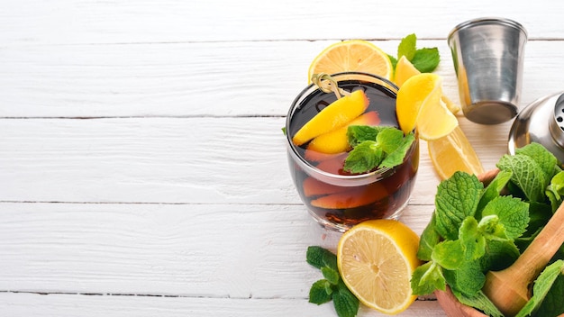 Alcoholic cocktail of whiskey lemon and mint RumCola Brandy On a white wooden background Free space for text