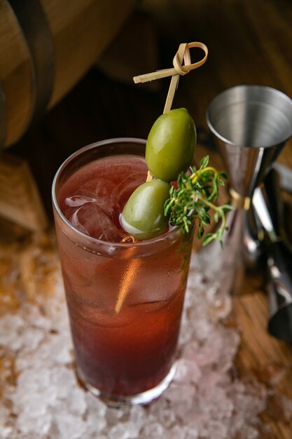 Alcoholic cocktail with ice, olives on a wooden table