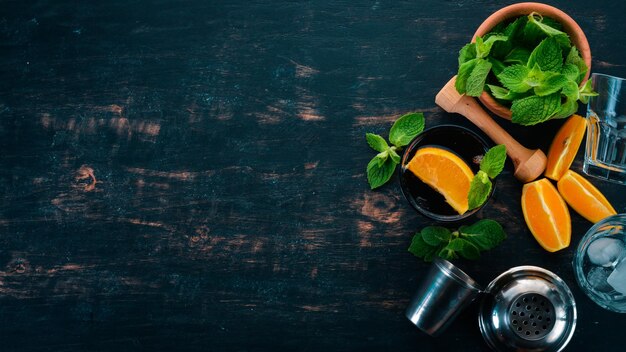 Alcoholic cocktail with orange and mint Negroni Long Island Rumcola On a black wooden background Free space for text