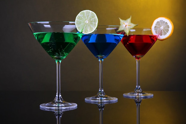 Alcoholic cocktails in martini glasses on dark yellow background