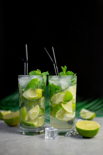 alcoholic drink mojito cocktail with lime and mint and palm leaf