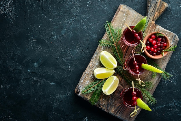 Alcoholic liqueur from a cranberry in a glass. Cranberry, lime, rosemary. On a rustic background. Top view. Free space for your text.