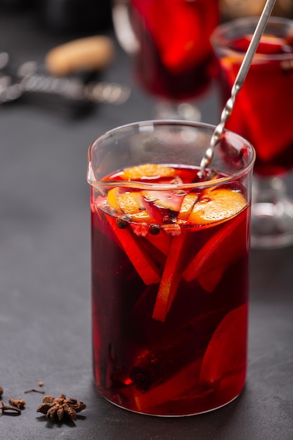 Alcoholic mulled wine with fruits and spices on a dark\
background, traditional alcoholic drink, christmas