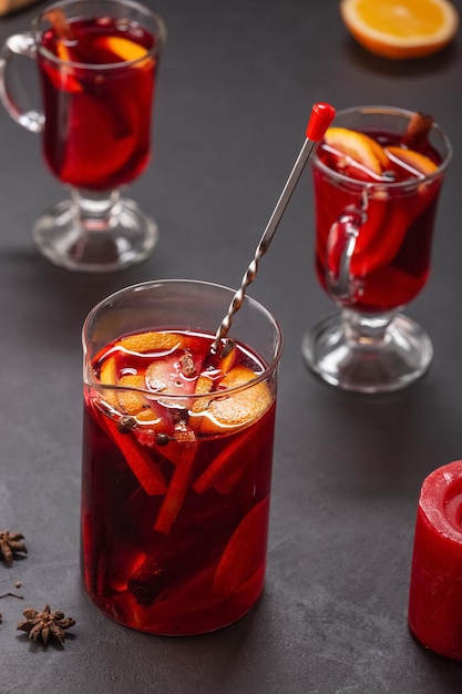 Alcoholic mulled wine with fruits and spices on a dark\
background, traditional alcoholic drink, christmas