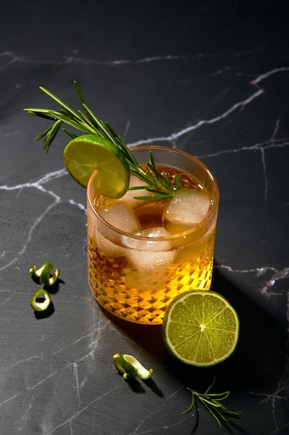 Alcoholic or nonalcoholic cocktail with lime and rosemary on a dark marble table