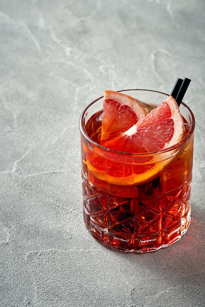 Alcoholic orange cocktail with oranges and ice in a glass Concrete background Aperol spritz