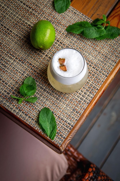 Alcoholic Peruvian cocktail Pisco Sour cocktail with ingredients with lemon on wooden background