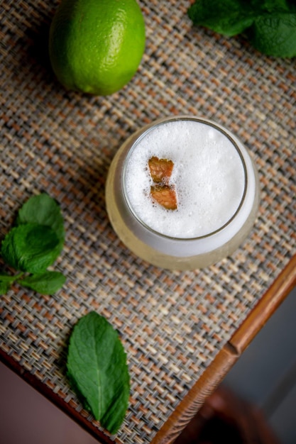 Alcoholic Peruvian cocktail Pisco Sour cocktail with ingredients with lemon on wooden background