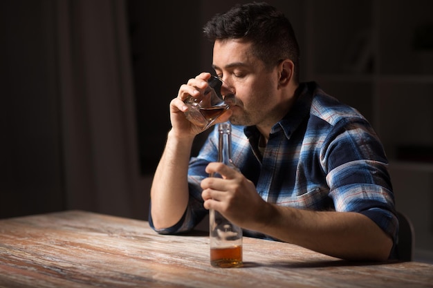 Foto alcolizzato con bottiglia che beve whisky di notte