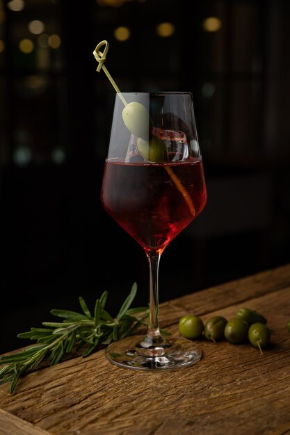 alcoholische cocktail met citroen en olijf op een houten tafel