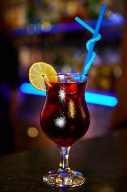 Alcoholische cocktail met cola-ijs en citroen op de bar