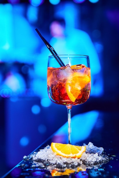 Alcoholische cocktail met ijs en een stuk sinaasappel op de toog