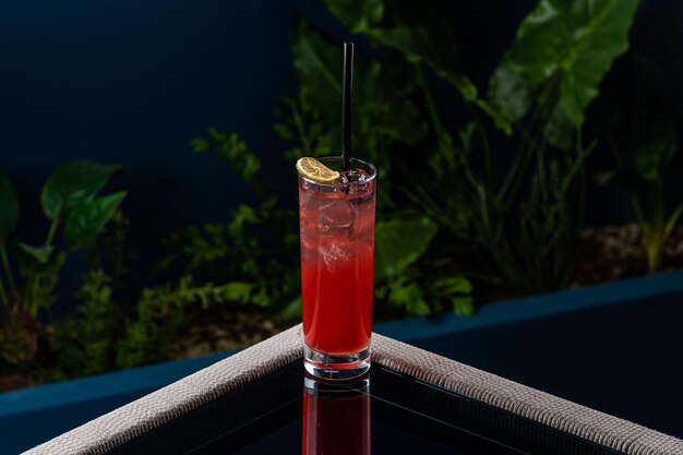 Alcoholische cocktail op een transparante tafel tegen een blauwe achtergrond en planten