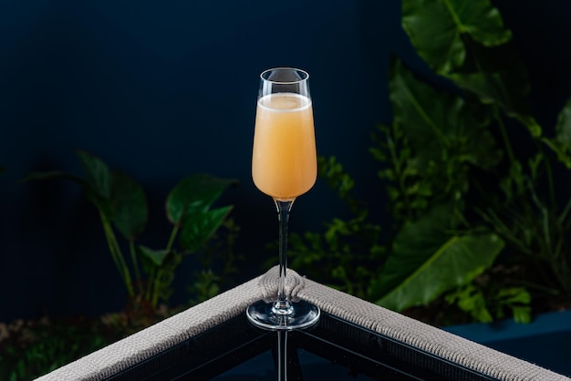 Alcoholische cocktail op een transparante tafel tegen een blauwe achtergrond en planten