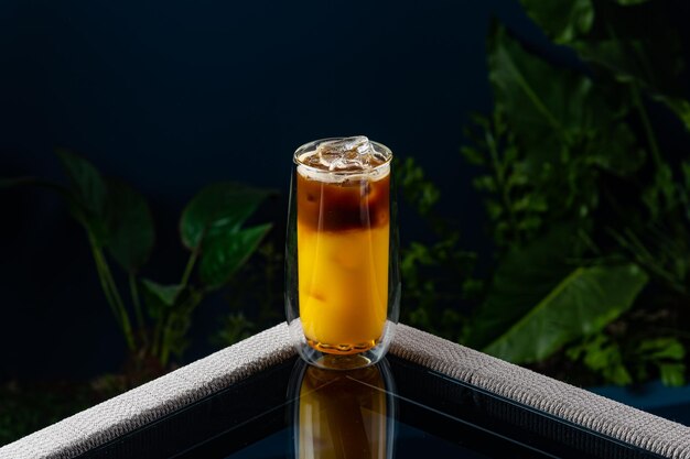 Alcoholische cocktail op een transparante tafel tegen een blauwe achtergrond en planten