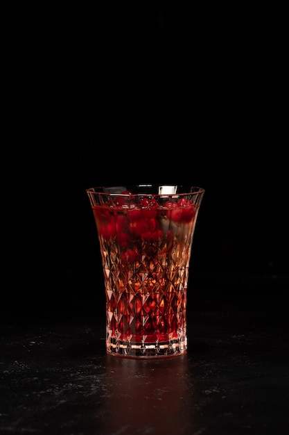 Alcoholische drank geschoten met cranberry-bessenstroop in een klein gefacetteerd glas