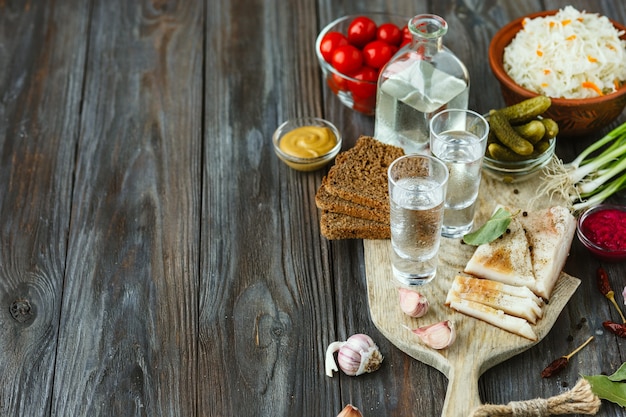 alcoholische drank met reuzel, gezouten groenten op houten achtergrond. Alcohol pure ambachtelijke drank en traditionele snack, tomaten, kool, komkommers. Negatieve ruimte. Eten vieren en lekker.