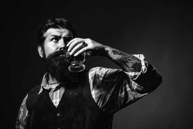 Alcoholische drank zelfverzekerde bebaarde man in zwart pak met glas whisky in loft man die alc . drinkt