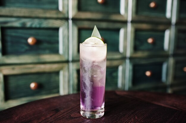 Alcoholische lange violette cocktail met ijs in glas bij barlijst