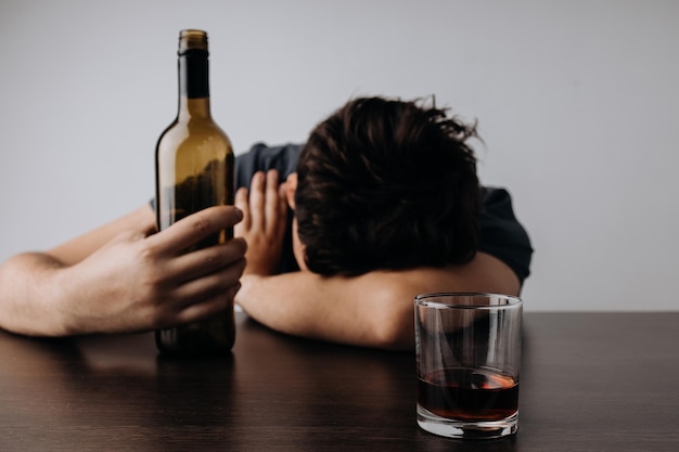 Alcoholism addiction and treatment concept Man with bottle and glass lying on a table