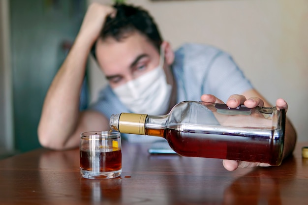알코올 중독, 알코올 중독, 그리고 사람들의 개념 - 집에 럼주 한 병을 든 남성 알코올 중독자. 심심해서 혼자 술에 취한 실직 전문의는 자가격리된다.
