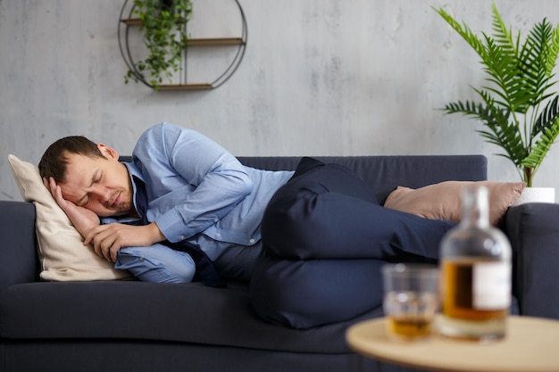 Photo alcoholism business and stress concept drunk businessman sleeping on sofa at home