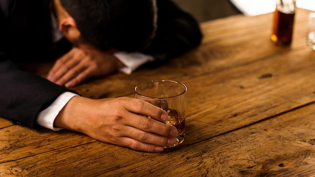 Alcoholisme depressieve aziatische jonge man slaapt op tafel terwijl hij alcoholische drank drinkt die 's nachts alleen glas whisky vasthoudt Behandeling van alcoholverslaving lijdt aan misbruikprobleem alcoholisme concept