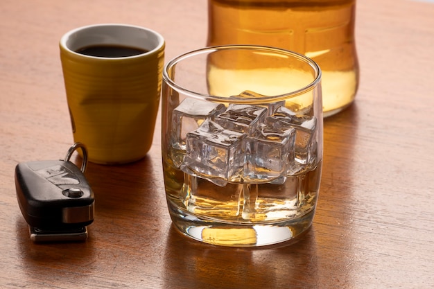 Alcoholmisbruik met glas whisky met ijs en autosleutel op tafel.