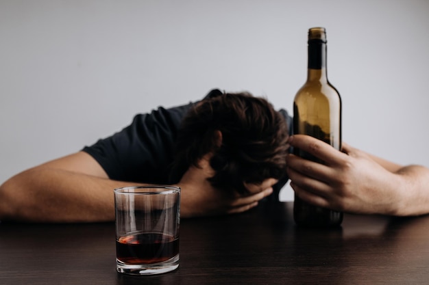 Alcoholverslaving en behandelingsconcept Man met fles en glas liggend op een tafel