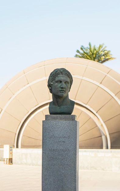 Alexander great of greece statue against the background of blue\
sky and palm trees in the city of alexandria egypt