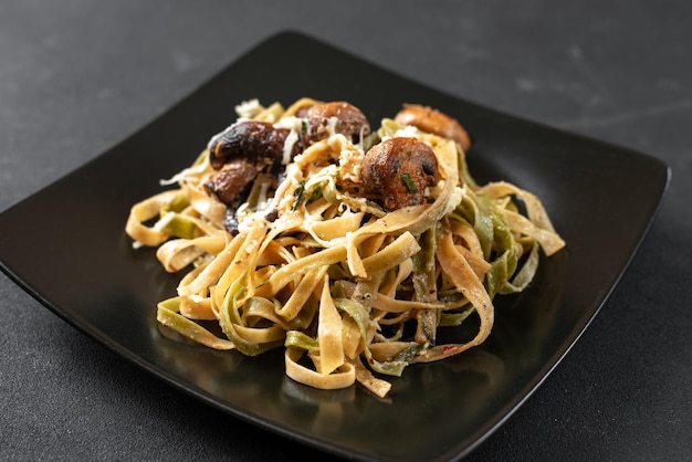 Alfredo pasta met champignons in roomsaus op een zwarte plaat op een donkere achtergrond klassieke italiaanse fe