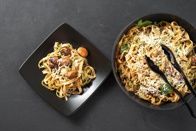 Alfredo pasta with mushrooms in cream sauce on a black plate on a dark background freshly cooked pas