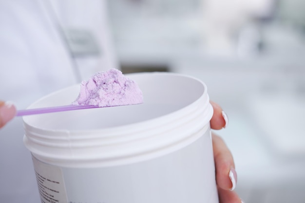 Alginaatmasker paars in een pot in vrouwelijke handen cosmetische apparaten voor de huid