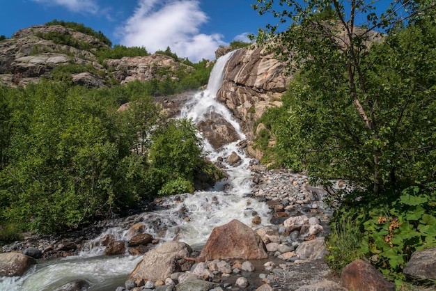 Alibek waterfall from the Alibek glacier on a sunny summer day Dombay KarachayCherkessia Russia