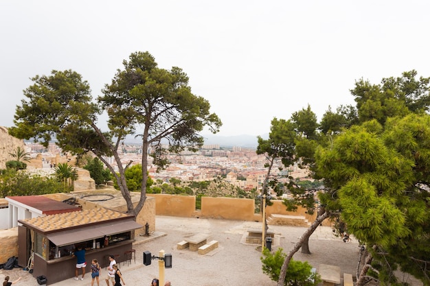 Foto alicante spanje 14 october 2023 uitzicht op de binnenkant van het kasteel van santa barbara toeristen wandelen in een openluchtcafé en groene bomen