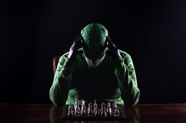 alien playing chess, black studio background