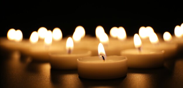 Photo alight candles in a row on black background