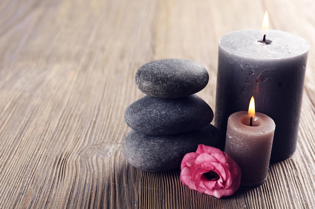 Alight wax grey candles with roses and pebbles on wooden background relax concept