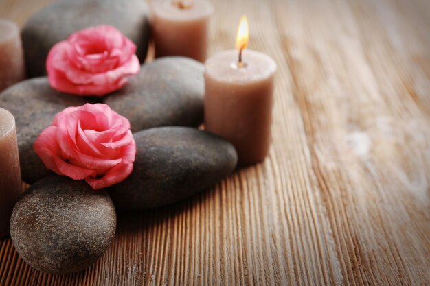 Alight wax grey candles with roses and pebbles on wooden background relax concept