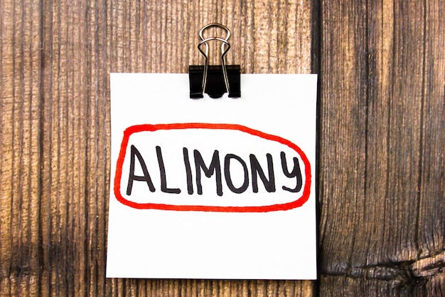 테이블 위의 종이에 있는 ALIMONY 텍스트 개념위자료 지불 개념