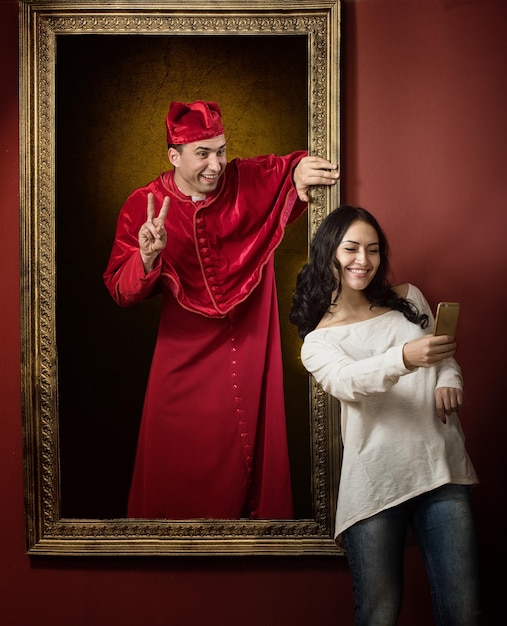 Alive portrait of a medieval priest and a visitor of the gallery taking selfie photo together