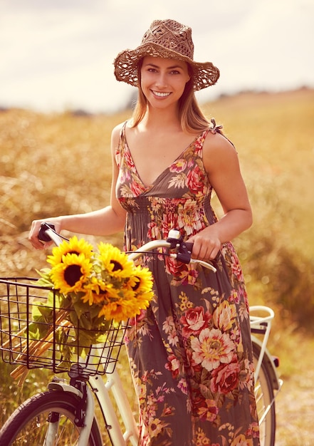 彼女に必要なのは自転車とひまわりの束で田舎をサイクリングする若い女性の素晴らしい屋外ショットです