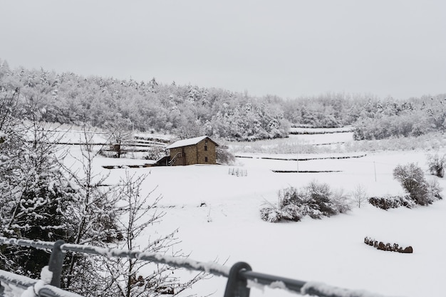 All-white landscape covered by snow and fog in northern Italy. Rustic stone house covered with snow